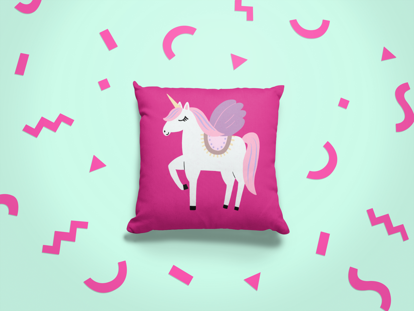 Pink pillow with a unicorn design on a light green background with pink geometric shapes