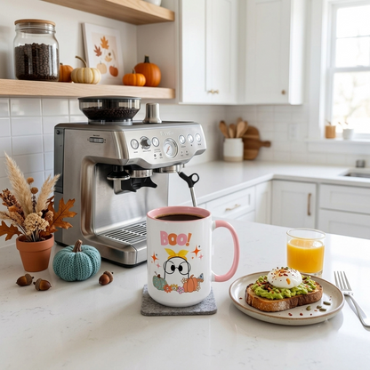 Cute Halloween ceramic mug featuring a smiling ghost wearing oversized glasses and a yellow bow with colorful pumpkins, flowers, and "BOO!" lettering. White mug with a pink handle and pink interior, available in 11oz flat-bottom and 15oz rounded-bottom sizes.