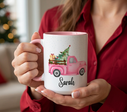 Personalized pink Christmas truck mug with custom name Sarah, featuring a vintage pink pickup carrying a Christmas tree and gifts in a snowy holiday scene.